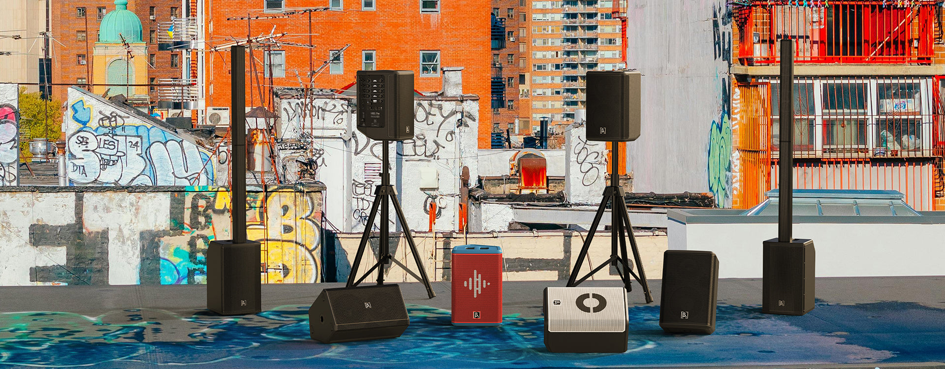 Outdoor setting with multiple speakers and a colorful mural in the background
