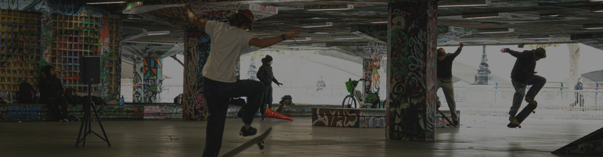 Skateboarders performing tricks in a skate park with graffiti-covered walls.